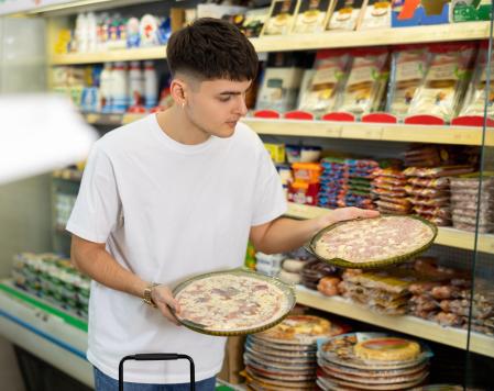El chico adquirió un montón de pizzas en un supermercado.