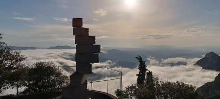 El monumento L'Escala de l'Enteniment con la madrugadora niebla de Montserrat.