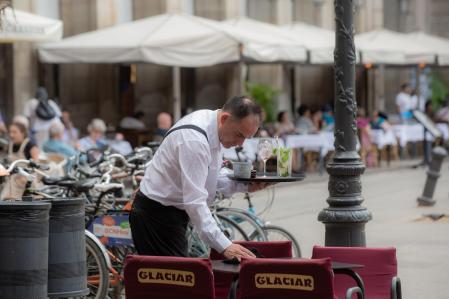 Un camarero limpia una mesa en la plaza Real de Barcelona