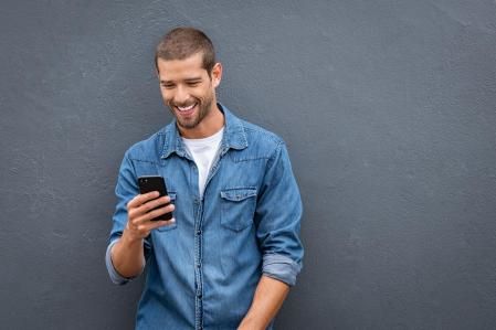 Un hombre mirando contento su teléfono móvil