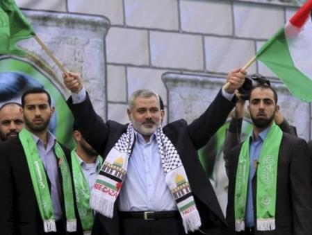 El jefe del Gobierno de Hamas en Gaza, Ismail Haniye, sostiene una bandera palestina y otra de Hamas durante un acto de conmemoración del vigesimo segundo aniversario de la fundación del movimiento islamista
