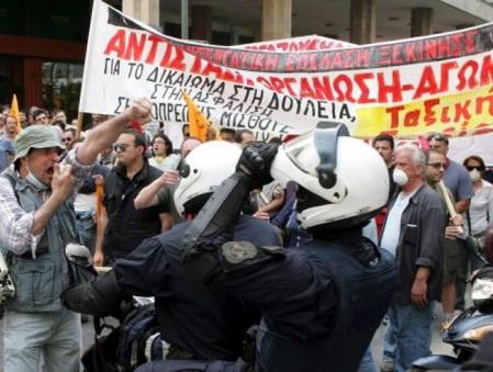 Unos agentes de la Policía antidisturbios se desplazan en moto entre un grupo de manifestantes durante un acto de protesta contra la política de austeridad del Gobierno griego en Atenas