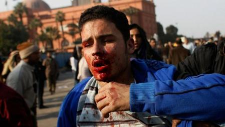 Un hombre herido huye de sus agresores en la plaza Tahrir de El Cairo