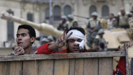 Un manifestante herido levanta una barricada en la plaza Tahrir mientras hace el signo de la victoria