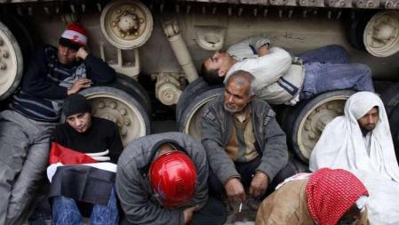 Manifestantes se sientan junto a un vehículo militar en la plaza Tahrir en El Cairo