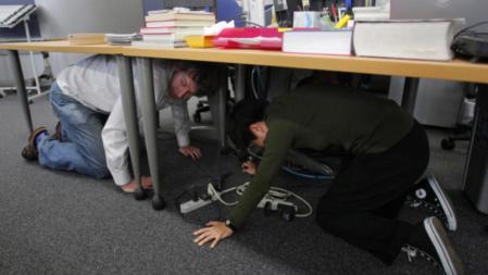 Dos redactores de la agencia de noticias AP se protegen bajo una mesa durante el terremoto de 8,8 grados en Japón.