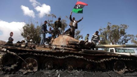 Los rebeldes libios celebran los bombardeos sobre un tanque de Gadafi, destrozado por los ataques