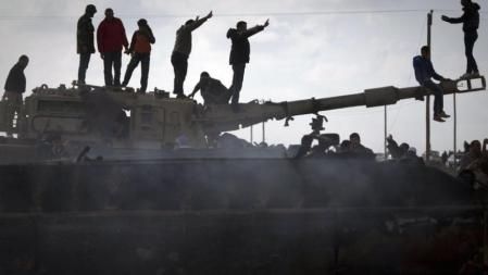 Ciudadanos libios celebran en Bengasi sobre un tanque abatido perteneciente a las fuerzas de Gadafi