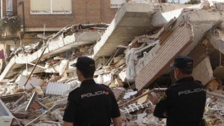 Dos agentes de la policía observan las ruinas de un edificio en Lorca.