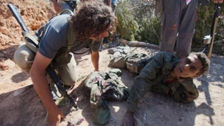 Un rebelde libio interroga a un soldado leal a Gadafi.