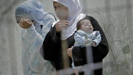 Una refugiada siria en el complejo de Yayladagi, al lado de la frontera siria, sostiene un bebé y camina junto a otra compatriota.