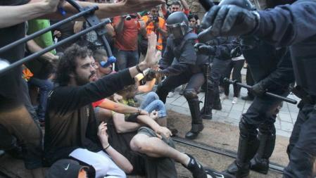 Dos mossos d'Esquadra intentan apartar a varios jovenes durante la concentración que estan realizando más de 2.000 