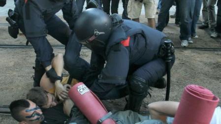 Dos mossos d'Esquadra intentan apartar a varios jovenes durante la concentración que estan realizando más de 2.000 
