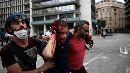 Un manifestante ensangrentado es ayudado durante las protestas en Atenas