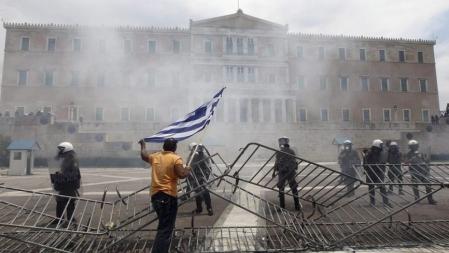 Un manifestante ondea una bandera griega frente a los policías antidisturbios que protegen el Parlamento de Grecia