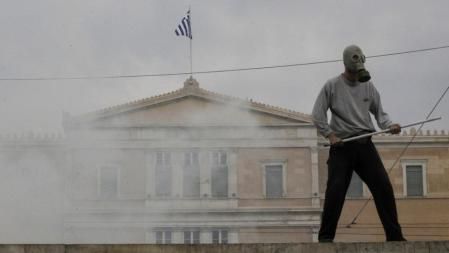 Un manifestante sujeta una barra de hierro frente al Parlamento griego durante las protestas contra el plan de austeridad