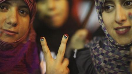 Mujeres libias muestran, en Bengasi, sus uñas pintadas con la bandera libia previa a Gadafi para celebrar los avances de la rebelión