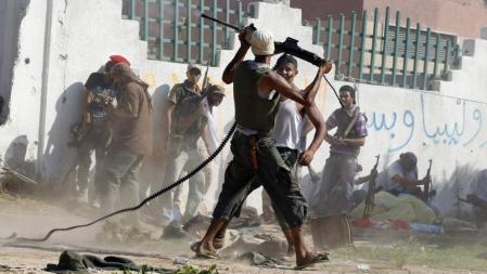 Un rebelde disparando un poco a voleo contra un francotirador gadafista en el barrio de Al Aziziya, donde ayer seguían los combates; Gadafi, escondido, también seguía lanzando llamamientos a 