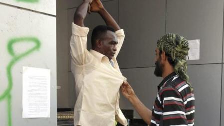 Un rebelde libio controla a un hombre acusado de ser un mercenario de Muamar Al Gadafi en un punto de control en Trípoli, Libia