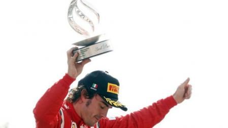 El piloto asturiano Fernando Alonso, tercero en Monza, levanta el trofeo en el podio