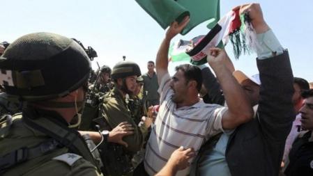 Un grupo de palestinos, rodeados por soldados israelíes, se manifiestan para exigen que Palestina sea aceptada como miembro con pleno derecho de la ONU