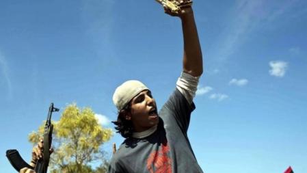 Mohamed El Bibi, de 20 años de edad, muestra la pistola chapada en oro que, supuestamente, pertenecía a Gadafi y que obtuvo al descubrir al líder libio refugiado en un agujero cerca de la ciudad de Sirte.