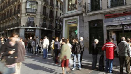 Un grupo de personas hace cola ante la administración de loterías de Doña Manolita, en la calle del Carmen, para comprar décimos para el sorteo extraordinario de Navidad de la Lotería Nacional