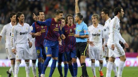 El árbitro le muestra la cartulina amarilla a Piqué ante la protesta de sus compañeros