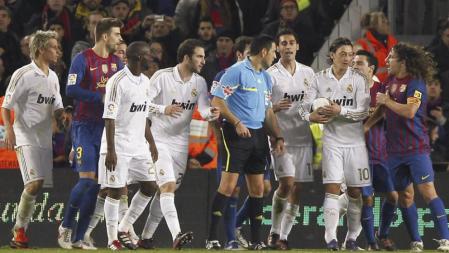 Los jugadores del FC Barcelona y del Real Madrid rodean al árbitro Teixeira Vitienes