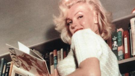 Marilyn Monroe en su apartamento, leyendo un libro titulado 