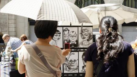 Unas turistas se protegen del sol con paraguas en la Rambla de Barcelona