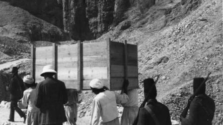 1922: Portadores autóctonos de un cajón lleno de tesoros de la tumba del faraón egipcio Tutankhamón en Tebas (actual Luxor y Karnak El) escoltado por soldados armados.