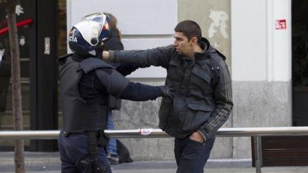 Un manifestante se enfrenta a un agente de la policía durante la huelga general en la zona de la Gran Vía y la calle Preciados, en Madrid