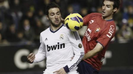 El delantero argentino del Real Madrid Gonzalo Gerardo Higuaín (i) recibe el balón ante un jugador del Osasuna