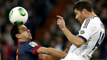 El centrocampista del Real Madrid Xabi Alonso (d) remata de cabeza ante el mediocentro del F.C. Barcelona Xavi Hernández durante el partido de ida de las semifinales de la Copa del Rey disputado esta noche en el estadio Santiago Bernabéu.