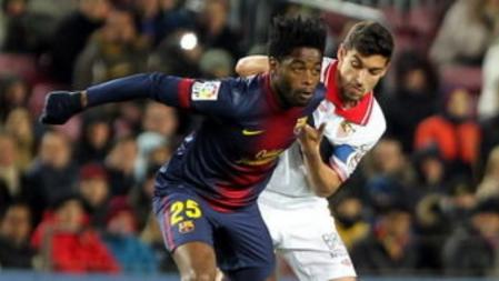 El centrocampista camerunés del FC Barcelona Alex Song trata de escapar a nte Jesús Navas, del Sevilla