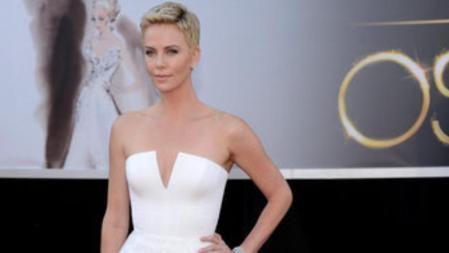 Charlize Theron con un traje blanco de Dior a su llegada a la alfombra roja de los Oscar 2013