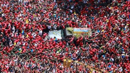 Miles de personas, ataviadas con camisas rojas, siguen el cortejo fúnebre del difunto presidente venezolano Hugo Chávez en su camino a la Academia Militar