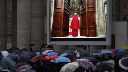 Centenares de personas observan a través de una pantalla de vídeo en la plaza de San Pedro el momento en el que monseñor Guido Marini cierra las puertas de la Capilla Sixtina para dar inicio al cónclave