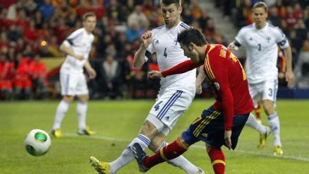 El delantero de la selección española David Villa lanza ante el defensa de Finlandia Joona Toivio