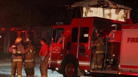 Un grupo de bomberos se reúne cerca de un complejo de apartamentos dañado tras la explosión de una fábrica de fertilizantes en West, Texas