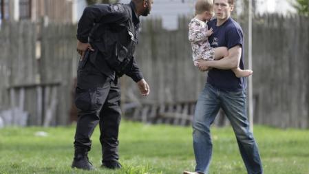 Un policía evacua a una familia en Watertown durante la operación policial para detener a los sospechosos del atentado en Boston