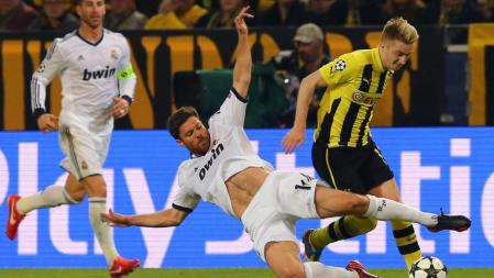 Xabi Alonso le intenta arrebatar el balón a Marco Reus