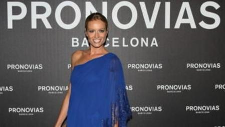 Renata Zanchi en el photocall de Pronovias con un vestido corto de gasa y guipur en color azul y escotado a un hombro.