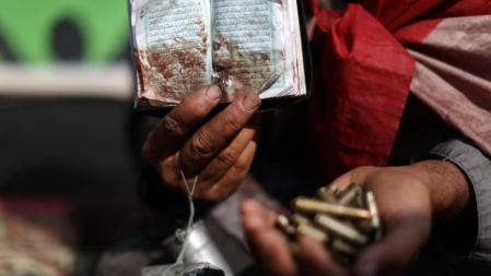 Un ciudadano egipcio que apoya al depuesto presidente Morsi muestra una copia ensangrentada del Corán y casquillos de bala