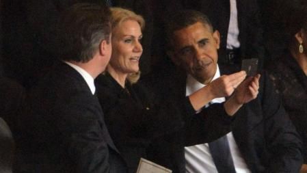 La primera ministra danesa, en un instante de la ceremonia en Soweto, ha sacado su teléfono móvil y, al parecer, ha pedido a Obama y al primer ministro británico, David Cameron, si podía sacarse una foto con ellos.