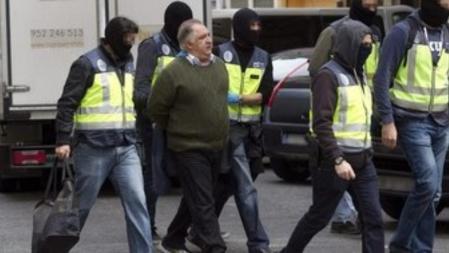 Varios miembros de la Policía Nacional trasladan a un detenido en la barriada malagueña de Las Delicias, al desarticularse la célula más importante responsable del envío de yihadistas a Siria y otras zonas de conflicto en una operación que se ha saldado, de momento, con siete arrestados.