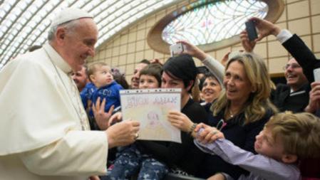 El Papa recoge el dibujo con el que le obsequia un niño en una audiencia con empleados en el Vaticano
