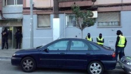 Agentes de la policía hacen guardia frente a la puerta de la vivienda de Badalona en la que vivía la familia que quería mandar a sus hijos a luchar a Siria