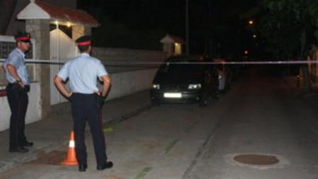 Dos agentes de los Mossos d'Esquadra controlan el cordón policial instalado en una calle de Castelldefels a raíz de la muerte de cuatro miembros de una familia